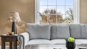 Un salon avec un canapé gris, une table basse en bois, une lampe et une plante en pot.