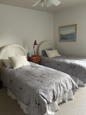 A bedroom with two single beds, a nightstand with a lamp, a wall-mounted painting, and a ceiling fan. - Homey 3-bedroom condo in cul-de-sac in Bethany Beach golf community (Bethany Beach)