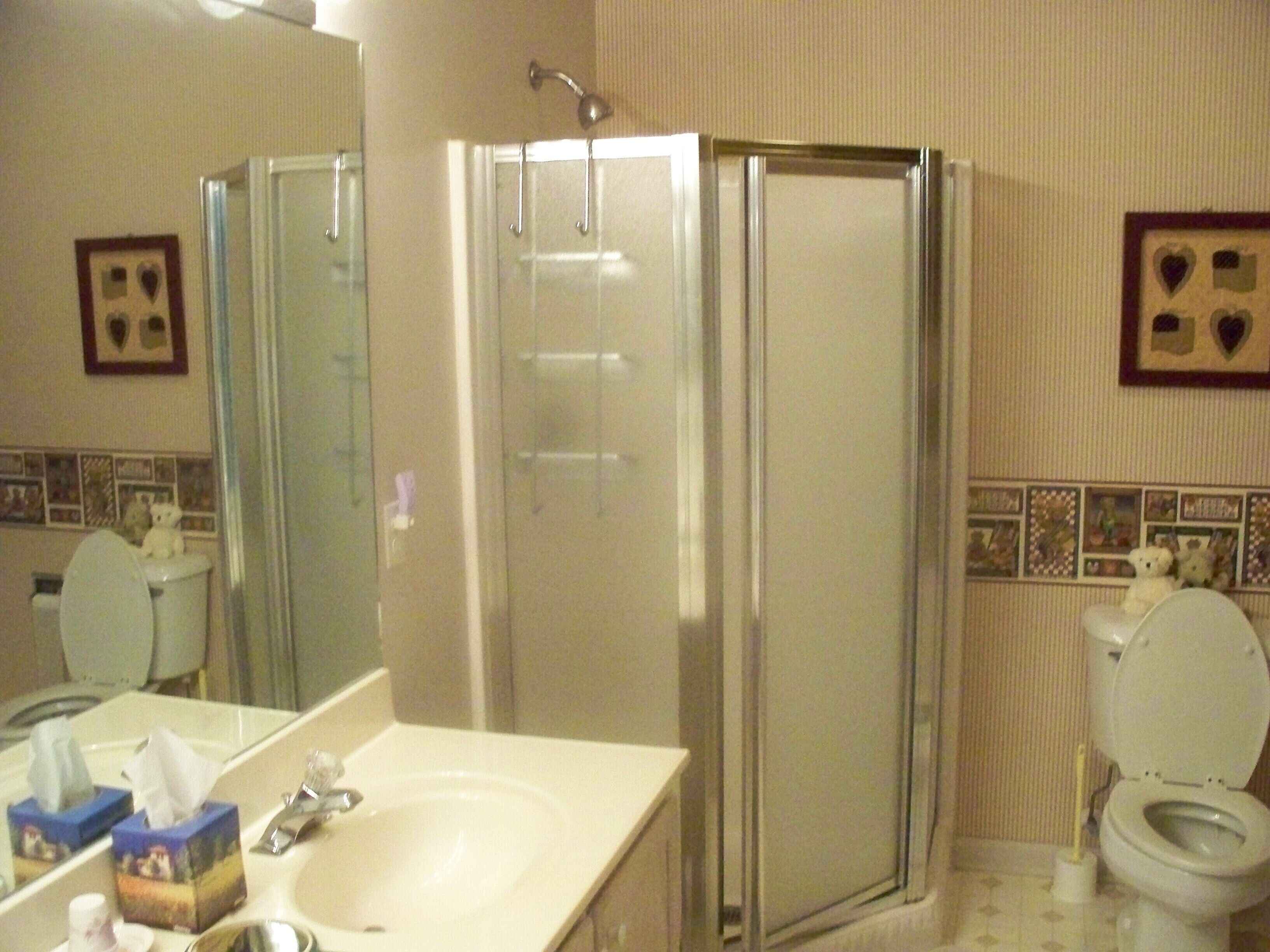 Ein Badezimmer mit Dusche, Toilette, Waschbecken und Spiegel.