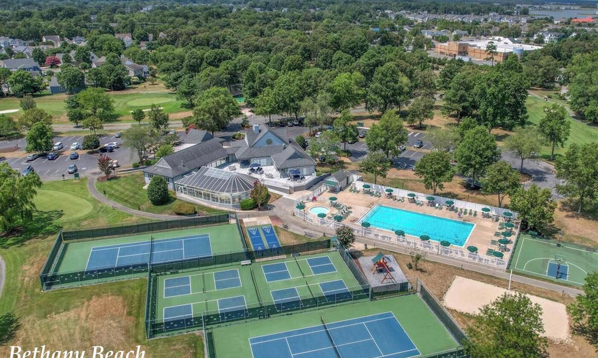 Ein Wohnhaus mit Tennisplatz, Schwimmbad und einer großen Villa mit Garage.