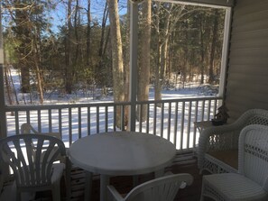 Un espace extérieur abrité, avec une table et des chaises, offrant une vue sur un paysage enneigé et boisé.