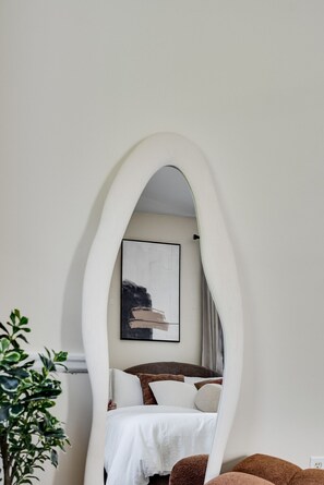 A bedroom with a bed, a mirror, and a painting on the wall. - Bright 1BR Near Queen’s, KGH & Waterfront! (Kingston)