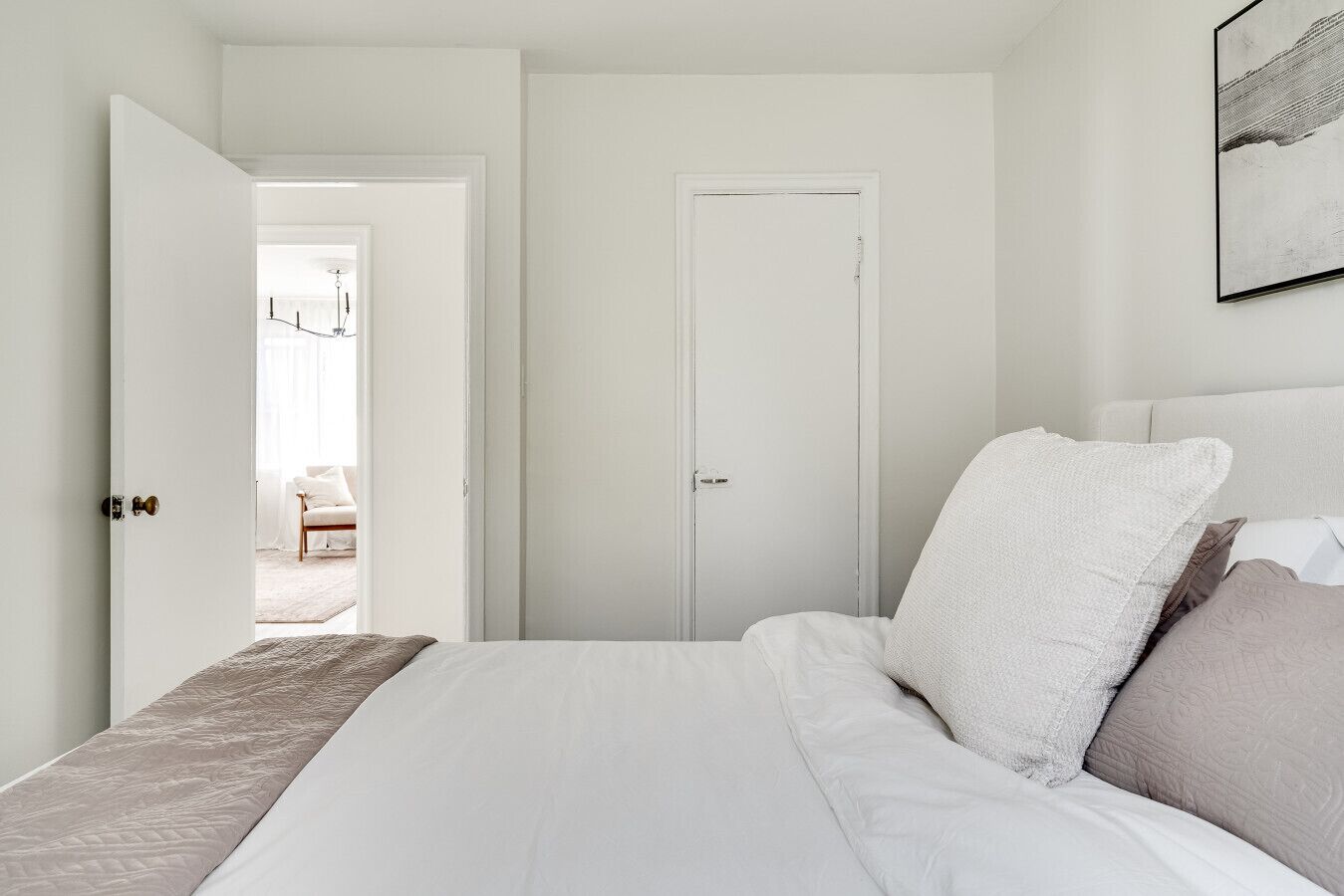 Een slaapkamer met een bed, een deur en uitzicht op een andere kamer.