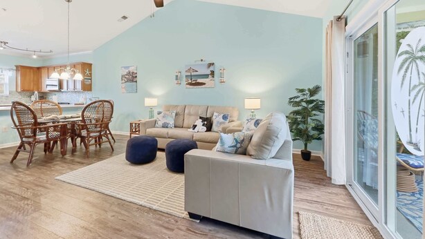 A spacious living area with a dining set, a sofa, and a ceiling fan. - Coastal Comfort Pet Friendly Barefoot Resort Villa (North Myrtle Beach)