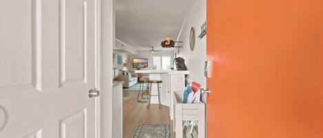 A hallway leading to a kitchen with a dining area, a ceiling fan, and a view of the living room.