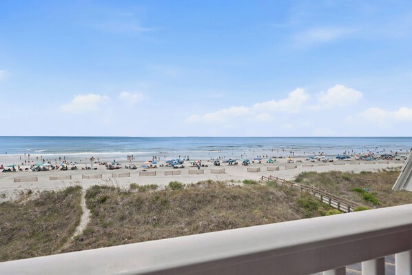 Ein Strand mit einer Holzzaun, einem Sandbereich und blauem Himmel.