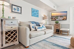 Een woonkamer met een bank, een dressoir, een televisie en kunstwerken aan de wanden.