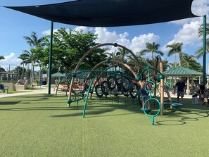 A playground with a climbing structure, benches, and a covered seating area.