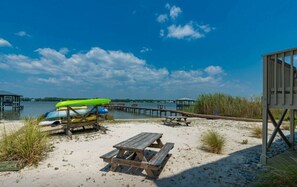 A beach with a wooden pier, a picnic table, and canoes. - Summer House West B105 (Gulf Shores)