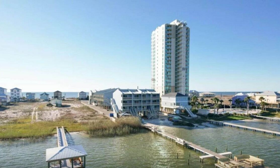 A coastal hotel with a tall building, a pier, and a beach area.