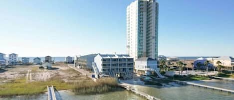Un hotel costero con un edificio alto, un muelle y una zona de playa.