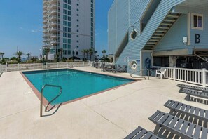 A swimming pool with lounge chairs and a building with a 'B' sign. - Summer House West B105 (Gulf Shores)