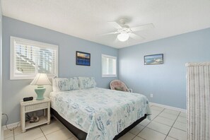 A bedroom with a bed, a nightstand, a lamp, a chair, and a ceiling fan. - Summer House West B105 (Gulf Shores)