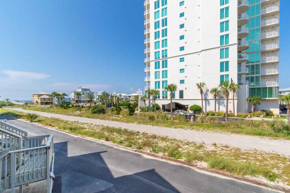 Ein mehrstöckiges Hotel mit Balkonen, einem Parkplatz und Blick auf den Strand.