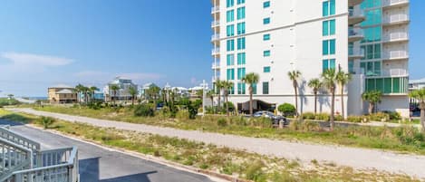 Ein mehrstöckiges Hotel mit Balkonen, einem Parkplatz und Blick auf den Strand.