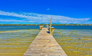 A wooden pier extending into clear water with a distant shoreline. - Summer House West B105 (Gulf Shores)