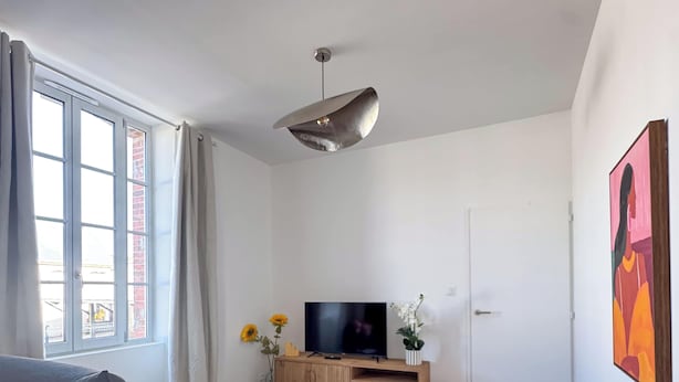 Una sala de estar moderna con un sofá, un televisor, una mesa de centro y un cuadro en la pared.