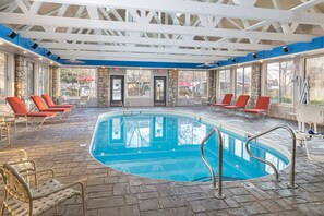 An indoor swimming pool with a stone floor, red lounge chairs, and a ceiling with white beams. - Spacious 2BR resort near Silver Dollar City, Table Rock Lake & Branson shows! (Branson)