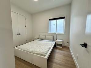 A bedroom with a bed, bedside tables, a window, and a wardrobe. - The Malbec Residence: Live Luxury with your Favourite People! (West Kelowna)