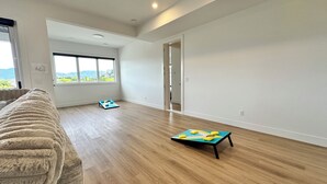 Una habitación espaciosa con suelo de madera, un ventanal grande y una puerta que da a otra estancia.