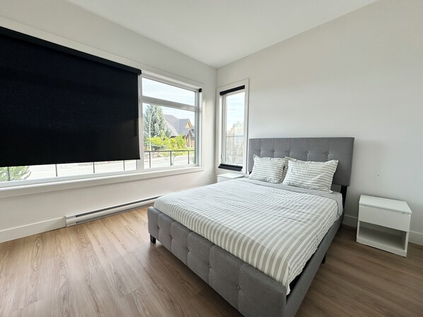 Ein Schlafzimmer mit einem Bett, einem Fenster mit Ausblick, einem Heizgerät und einem weißen Nachttisch.