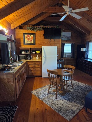 A cozy kitchen with wooden cabinets, a refrigerator, a microwave, and a dining area with chairs and a table.