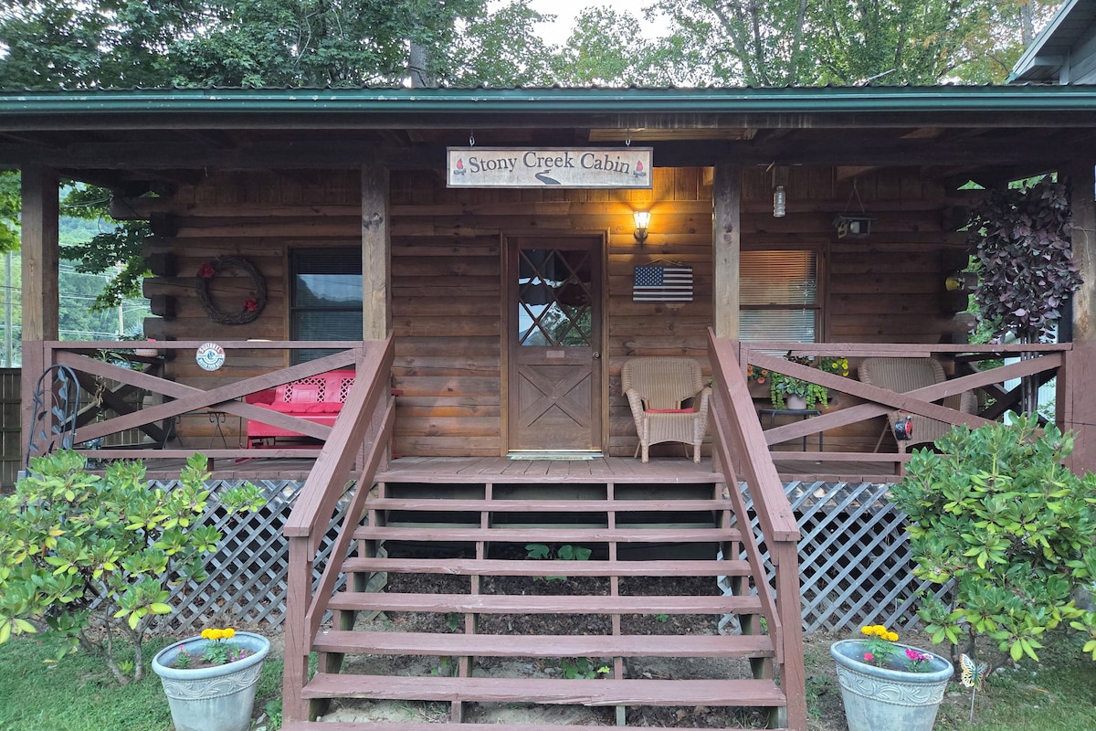 Una cabaña de madera con un porche, una escalera que lleva a la entrada y plantas en macetas.