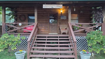 A wooden cabin with a porch, a staircase leading to the entrance, and potted plants.
