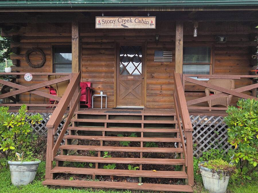 A cabin with a wooden exterior, a front porch, and a sign reading 'Stony Creek Cabin.'