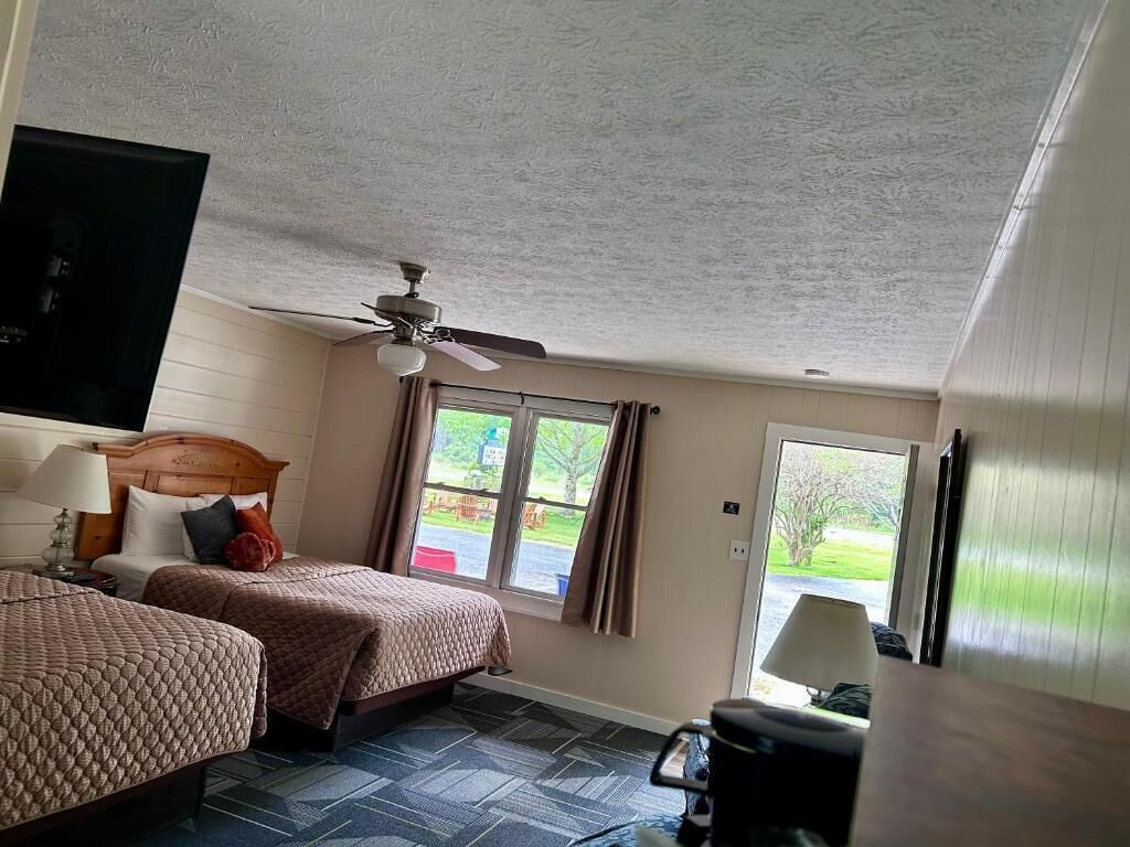Habitación de hotel con dos camas, un ventilador de techo, un ventanal y vistas al exterior.