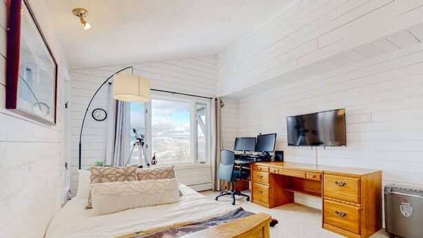 Quarto com cama, escrivaninha, computador e telescópio.