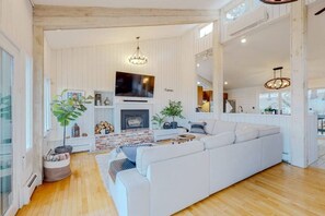 Ein geräumiges Wohnzimmer mit einem großen, weißen Sofa, einem Kamin und einem Fernseher.