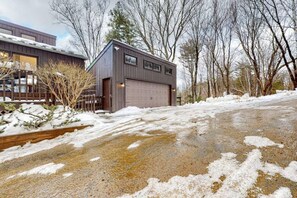 Ein Wohnhaus mit Garage, Auffahrt mit Schneeflecken und Holzzaun.