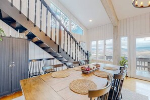 Ein Essbereich mit einem Holztisch, gewebten Untersetzern und einer Treppe mit schwarzer Geländer.