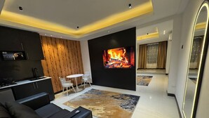 Ein modernes Wohnzimmer mit Fernseher, Kamin, Sofa und Essbereich.