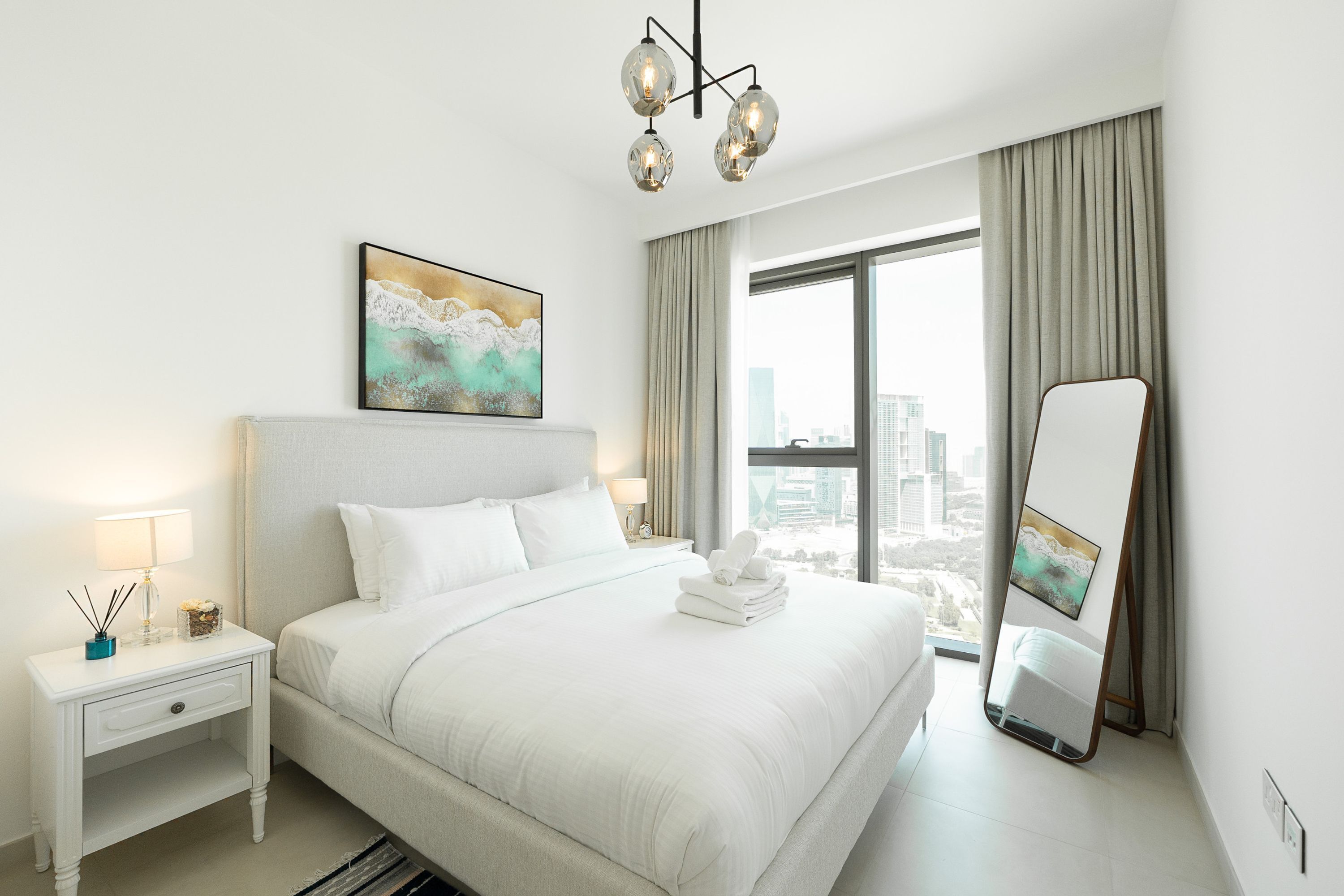 Une chambre d’hôtel avec un grand lit, une table de chevet, un miroir et une vue sur la ville.