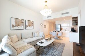 A modern living room with a sofa, coffee table, and artwork on the wall. - Elegant 1BR Apt, Steps Away from Dubai Mall (Dubai)