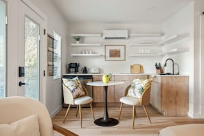 A modern kitchen with white cabinetry, a round dining table, two wicker chairs, and built-in shelving above the counter. - Onyx & Oak - Hot Tub & Backyard Oasis, East Austin (Austin)
