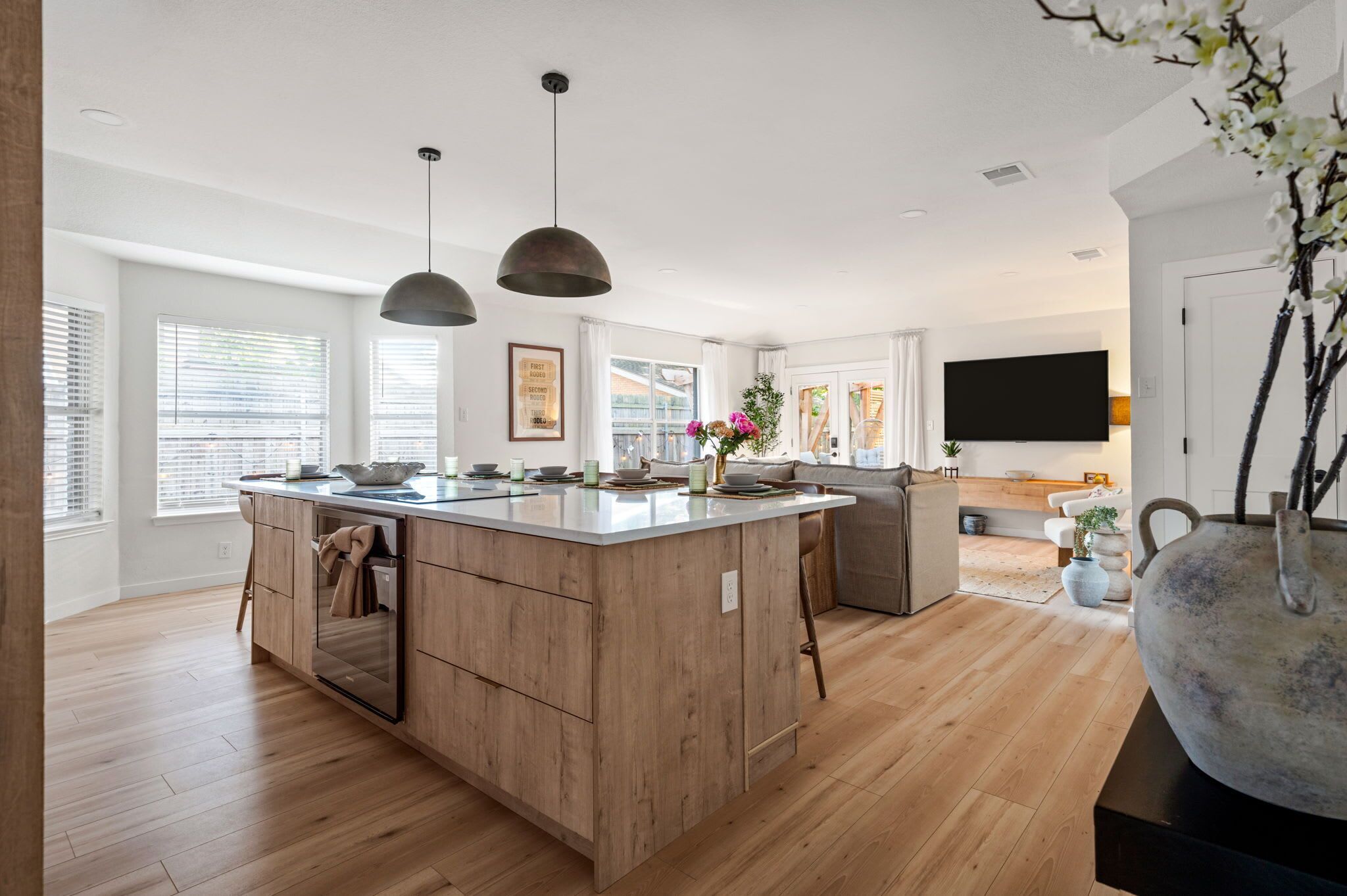 Une cuisine moderne avec des meubles en bois, des luminaires suspendus et un grand îlot central.