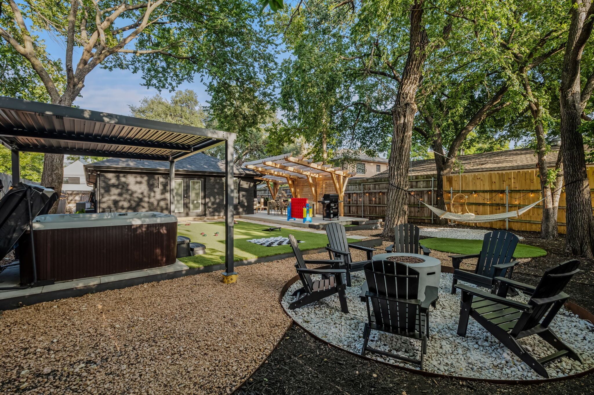 Ein Garten mit Whirlpool, überdachter Sitzbereich und Gartenmöbeln.