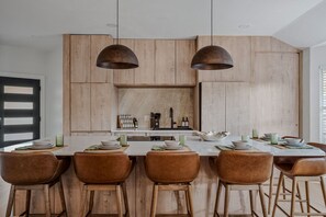 A modern kitchen with wooden cabinets, a central island, and pendant lighting. - Onyx & Oak - Hot Tub & Backyard Oasis, East Austin (Austin)
