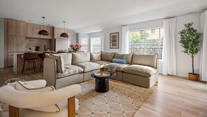 Ein modernes Wohnzimmer mit einer Couch, einem Couchtisch und einem Essbereich mit einer Küche im Hintergrund.