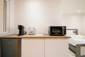 Eine kleine Küchenzeile mit Kaffeemaschine, Mikrowelle und Kühlschrank.