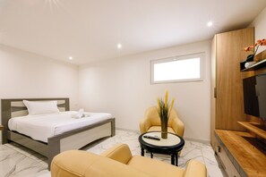 A hotel room with a bed, a chair, a small table, a TV, and a window. - Aventurine Studio 7 (Cannes)