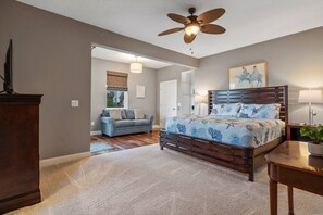 Ein Schlafzimmer mit einem Bett, einem Deckenventilator, einem Nachttisch aus Holz und einem Schreibtisch.