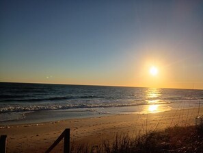 Ein Strand mit untergehender Sonne über dem Meer, der eine ruhige und friedliche Atmosphäre schafft.