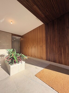 A modern interior with a wooden wall, a tiled floor, and a potted plant. - Entrecubos Apartments - Olhão City Center (Olhão)