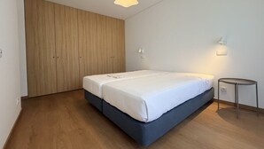 Un dormitorio con cama, armario, mesita de noche y lámpara colgante.