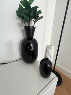 A white table with two black vases, one with a plant and the other empty, and a floor lamp. - The Lyall - 1 Bedroom (London)