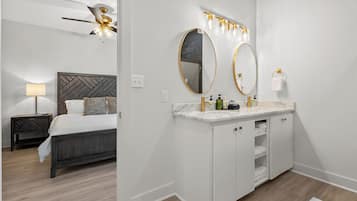 A modern bathroom with a large mirror, vanity, and a ceiling fan.